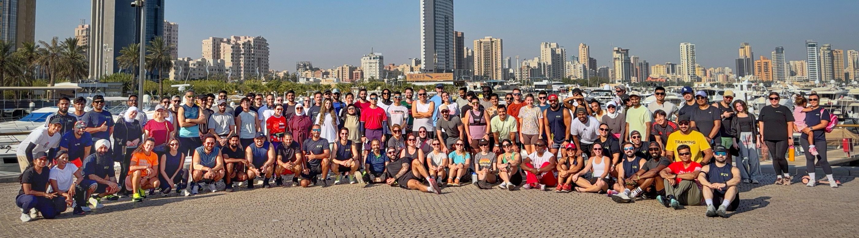 About a hundred Morning Milers runners gathered at a marina with the Kuwait City skyline behind them.